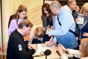 Na zdjęciu Adam Wajrak podpisuje książki.