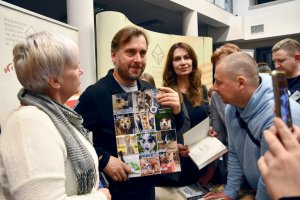 Na zdjęciu Adam Wajrak podpisuje książki.