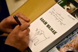 Na zdjęciu Adam Wajrak podpisuje książki.